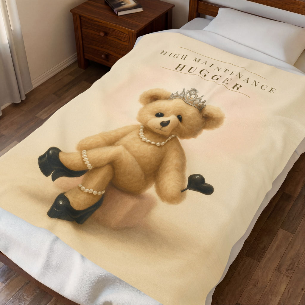 The 50 by 60 inch High Maintenance Hugger blanket draped over a made bed in a warm bedroom, showing sofa throw scale.