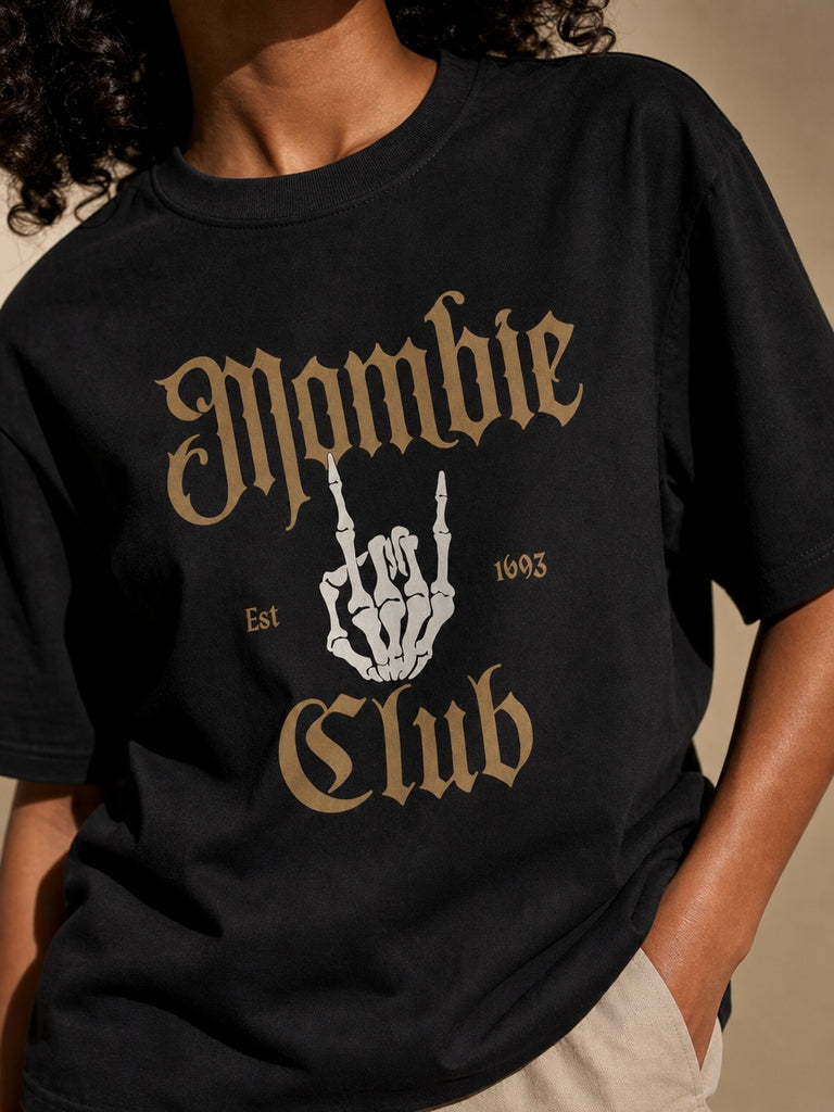 Close detail of the black Mombie Club tee with antique gold blackletter lettering and a skeleton hand