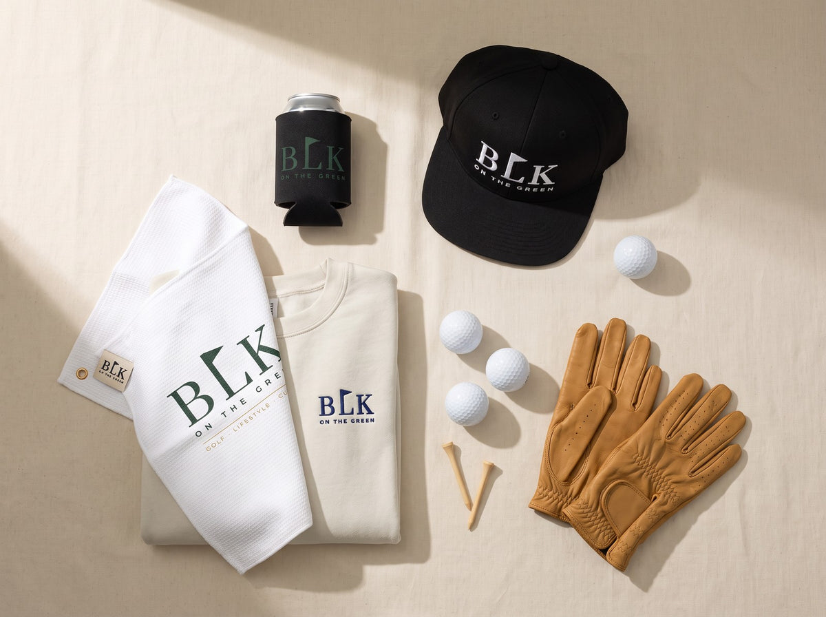Flat lay of the BLK on the Green Cart Cooler, Tee Box Snapback, Caddie Towel and sweatshirt