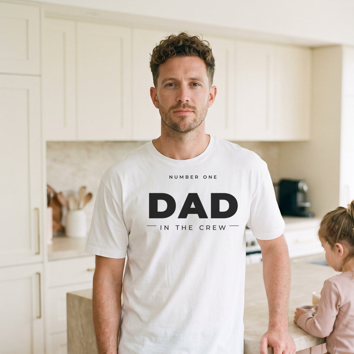 Man wearing the #1 Dad in the Crew tee in white in a bright cream kitchen with his daughter
