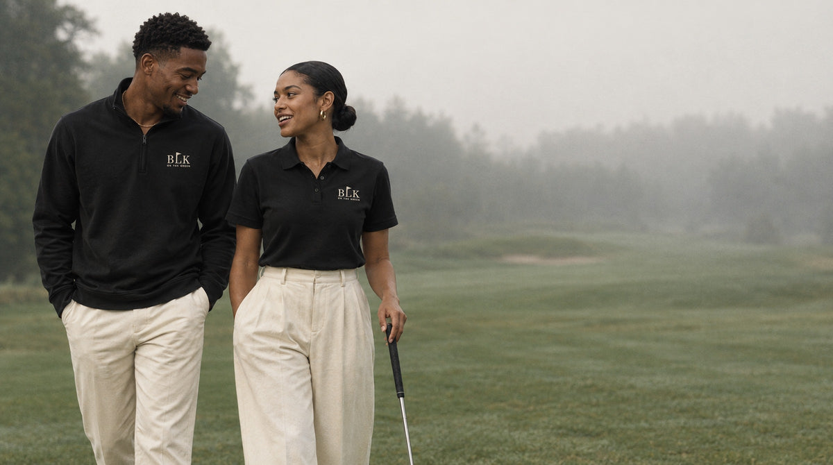 Two young Black friends in BLK on the Green black quarter zip and polo walking a misty fairway